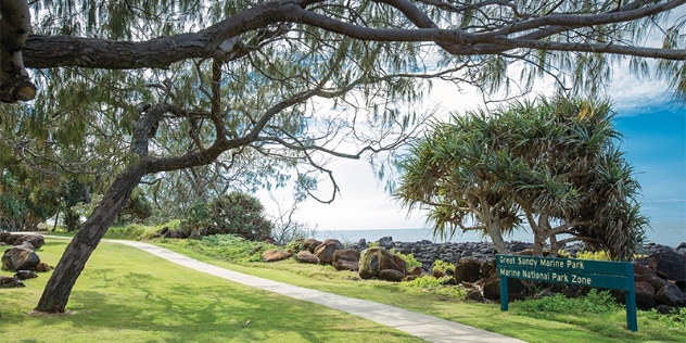 beachside path with view of water and signpost for the Great Sandy Marine Park