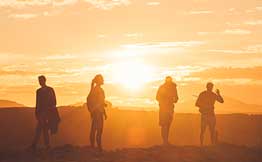 Four people standing in front of an orange sunset