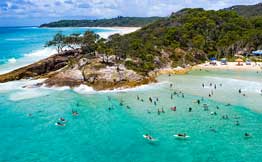 lots of people in aqua water around a headland