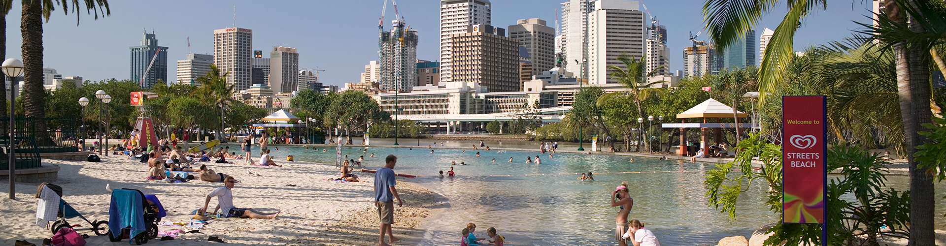 people wading in a man made beach sitting underneath Brisbane's high rise buildings