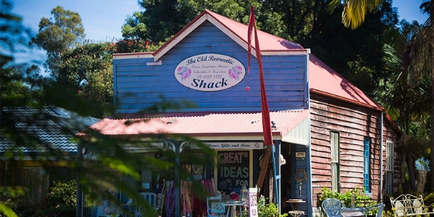 front view of historic red cedar building with the frontage painted mid blue with tables and chairs and scarves outside