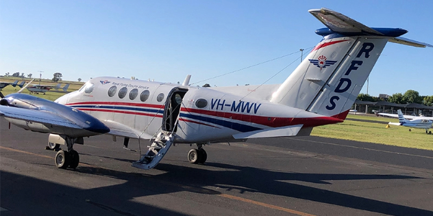 small white aeroplane with a red and blue stripe on the side sits on the runway with stairs open for museum visitors to enter