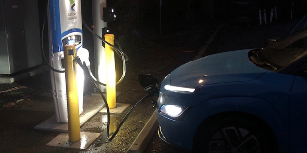 mid blue Hyundai Kona EV plugged at a public charger