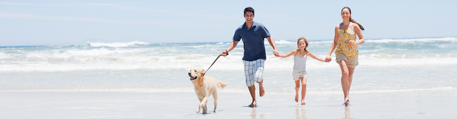 Family with dog running on beach