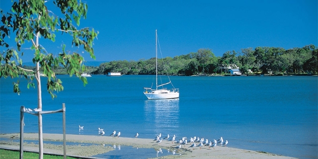 a white sailing boat floats on clear blue water