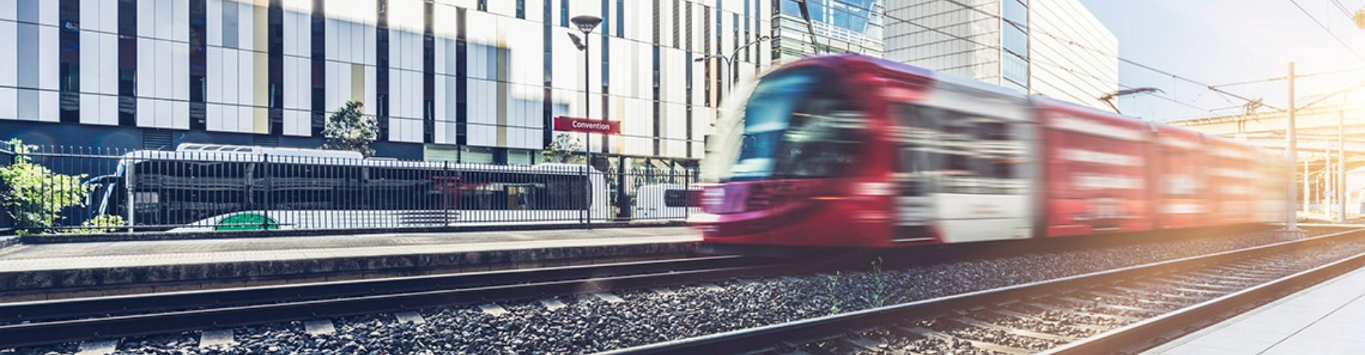 Blurred side view of a red light rail darting along the tracks.