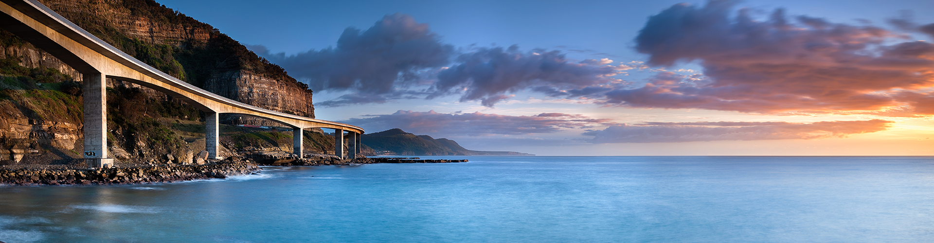 A bridge extending along a cliff, overhanging the sea