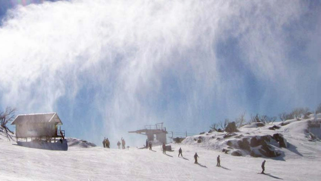 The top of a sunny, rocky ski hill in the Snowy Mountains, with a small chalet and lift.