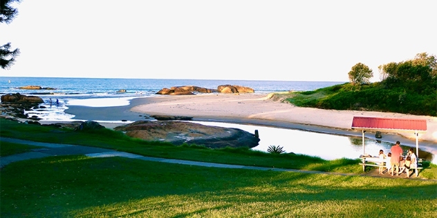 grassy area with a family enjoying a picnic at a public picnic table with ocean views