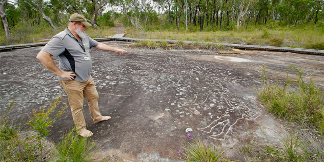  Tim Selwyn, operator of Girra Girra tours, points at a figure drawn into a rock of of a woman and kangaroo.