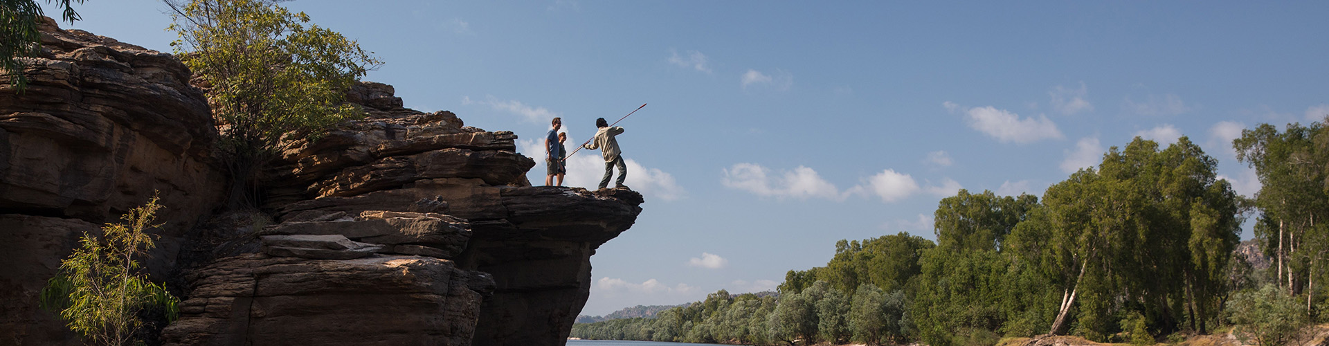two people spear fishing on the top of a rock cliff