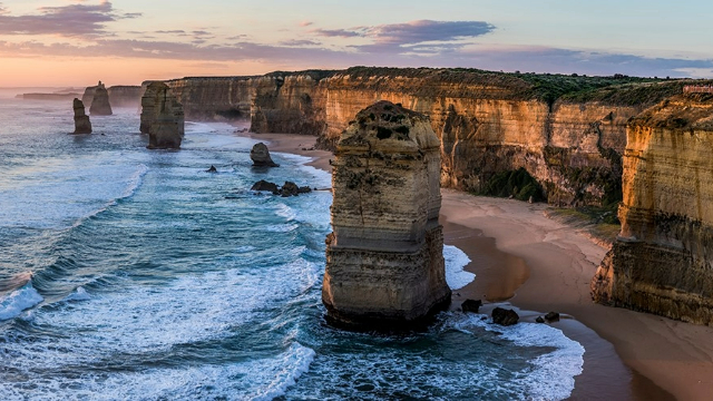 Panoramic view of a warm orange sunset over the ocean and twelve apostles rock formations in Victoria State.