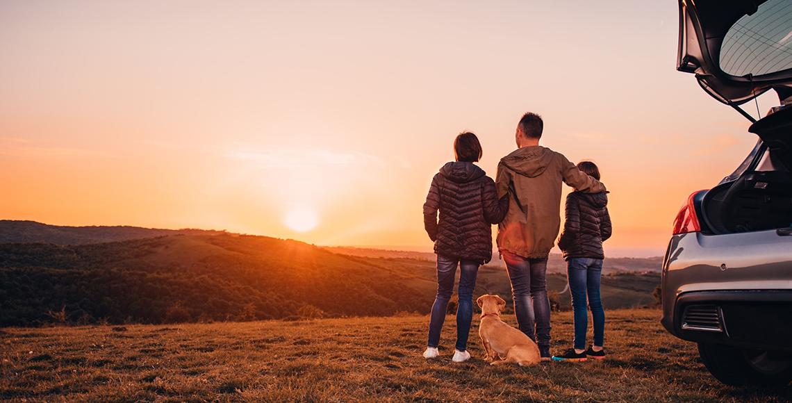 Family watching sunset on road trip