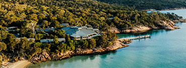 Aerial view of a coastal lodge at Freycinet with mountains and blue water