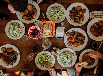 A group of friends around a table, sharing food and laughter in a warm, inviting dining setting