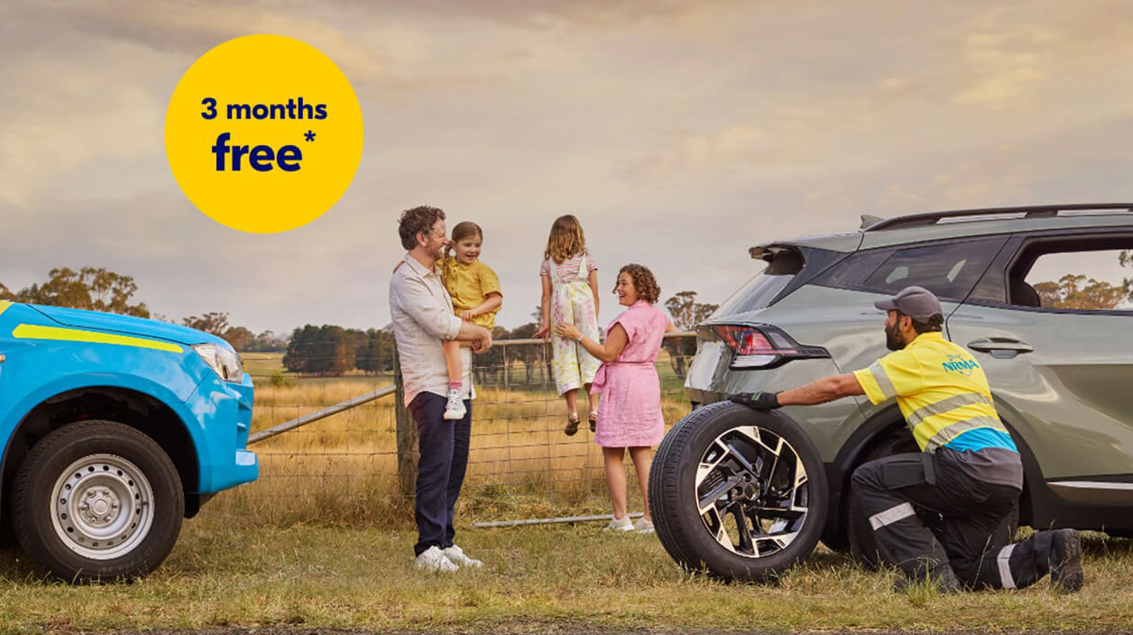NRMA Roadside assistance staff member helping to replace tyre for vehicle on the side of the road while family of four look on